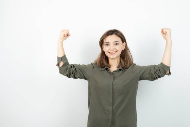 Sıradan kıyafetli güzel genç bir kadın kaslarını gösteriyor. Yüksek kalite fotoğraf