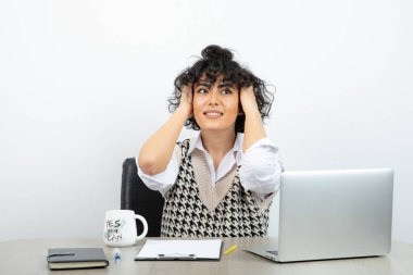 Esmer iş kadını sabit bir şekilde masada oturuyor ve bakıyor. Yüksek kalite fotoğraf
