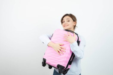 Kadın turist ayakta ve pembe seyahat valizine sarılıyor. Yüksek kalite fotoğraf