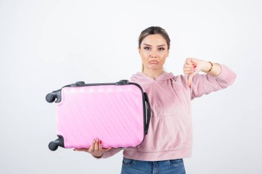 Güzel bir kadının pembe bir valiz tutarken ve baş parmağını kaldırırken fotoğrafı. Yüksek kalite fotoğraf