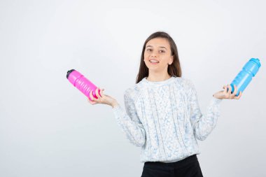 Beyaz arka planda plastik şişelerle poz veren süveter giyen kız