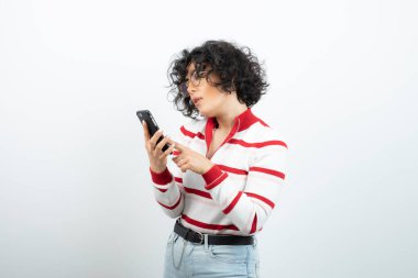 Kıvırcık saçlı genç kadın cep telefonundan mesaj okuyor. Yüksek kalite fotoğraf