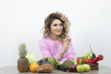 Masada çeşitli meyve ve sebzelerle poz veren güzel bir kadın.