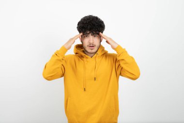 Sarı kapüşonlu adam beyaz arka planda poz veriyor.