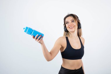  Şişeli kulaklıklı genç bir kadın.