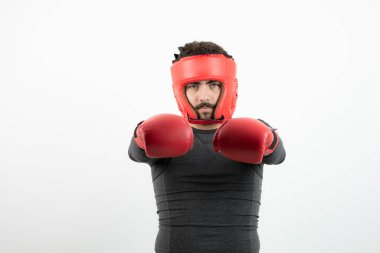 Beyaz duvarın üzerinde boks kaskı ve eldivenleri olan genç bir adamın portresi. Yüksek kalite fotoğraf