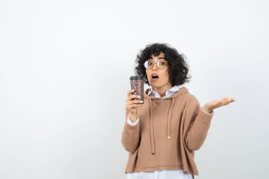 Tekrar kullanılabilir kahve fincanıyla poz veren genç bir kadın.