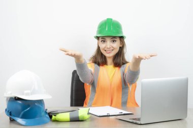 Üniformalı işçi kadın masada oturuyor ve açık avuç içlerini gösteriyor. Yüksek kalite fotoğraf