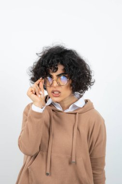 Kıvırcık saçlı, gözlüklü kadın komik surat yapıyor.