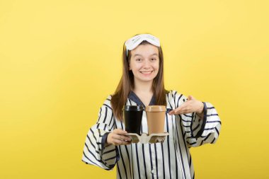 Pijama giyen ve elinde bir karton sıcak çay tutan güzel, uykucu bir kadın. Yüksek kalite fotoğraf