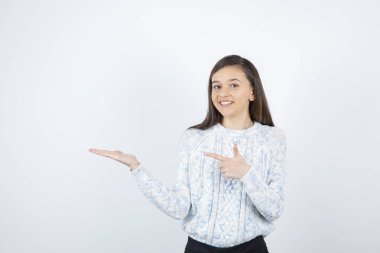 Beyaz arka planda duran süveter giyen kız