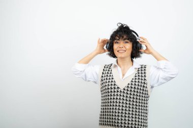 Esmer, kıvırcık saçlı, kulaklıklı, şarkı dinleyen kadının portresi. Yüksek kalite fotoğraf