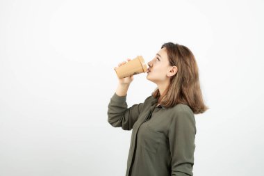 Kısa saçlı genç kız beyazdan önce bir fincan latte içiyor. Yüksek kalite fotoğraf