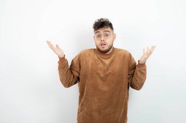 Beyaz duvarın üzerinde duran ve poz veren genç erkek modelin fotoğrafı. Yüksek kalite fotoğraf