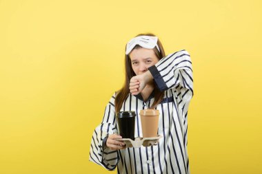 Pijama giyen ve elinde bir karton sıcak çay tutan güzel, uykucu bir kadın. Yüksek kalite fotoğraf