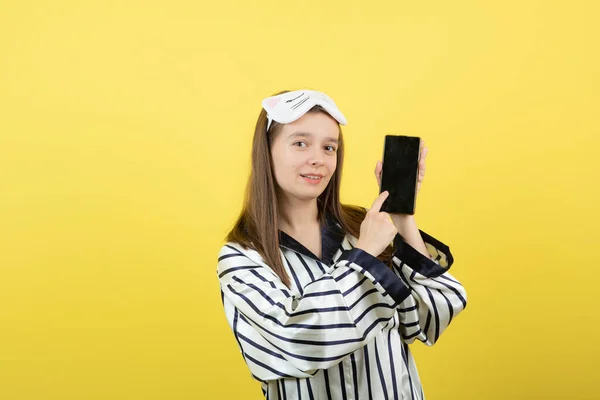 Teenager Girl Pajamas Pointing Her Mobile Phone Yellow Wall High — Stock Photo, Image