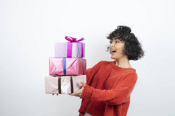 Curly beautiful woman in red sweater holding gift boxes. High quality photo