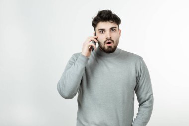 Akıllı telefonda beyaz duvara karşı konuşan çekici adamın portresi. Yüksek kalite fotoğraf