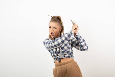 Beyaz bir duvarın üzerinde fırça tutan ve poz veren genç bir sanatçının portresi. Yüksek kalite fotoğraf