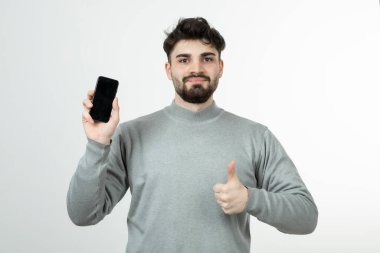 Akıllı telefonu tutan ve parmağını kaldıran çekici bir adamın portresi. Yüksek kalite fotoğraf