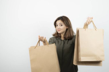 Beyazların üzerinde duran el işi çantaları olan genç bir manken resmi. Yüksek kalite fotoğraf