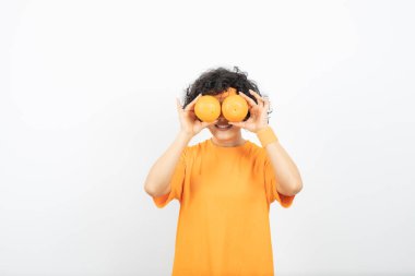 Turuncu tişörtlü kadın portakallarla poz veriyor.