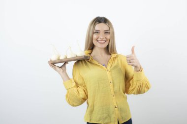 Sarı bluzlu güzel bir kadının şalgam tutup baş parmağını kaldırdığını hayal et. Yüksek kalite fotoğraf