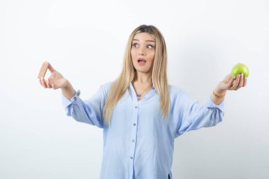Beyaz arka planda yeşil elma tutan genç bir kızın portresi. Yüksek kalite fotoğraf