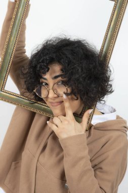 Kıvırcık esmer, komik bir kadın. Boş resim çerçevesiyle poz veriyor.
