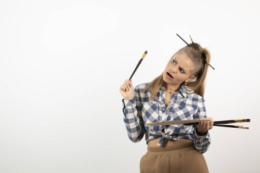 Genç sarışın ressam kız beyaz bir duvarın üzerinden ne çizeceğini düşünüyor. Yüksek kalite fotoğraf