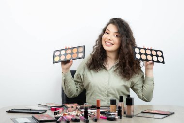 Makyaj malzemeleriyle masada oturan genç bir kadın. Yüksek kalite fotoğraf