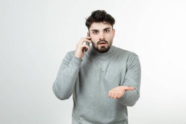 Akıllı telefonda beyaz duvara karşı konuşan çekici adamın portresi. Yüksek kalite fotoğraf