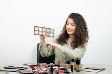 Makyaj malzemeleriyle masada oturan genç bir kadın. Yüksek kalite fotoğraf