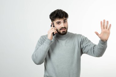 Akıllı telefonda beyaz duvara karşı konuşan çekici adamın portresi. Yüksek kalite fotoğraf