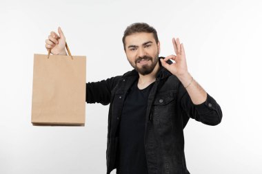 Genç, yakışıklı bir adam işaret levhası ve kese kağıdı taşıyor. Yüksek kalite fotoğraf