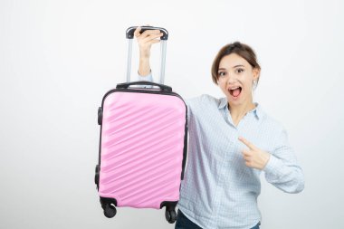 Ayakta duran ve pembe seyahat çantasına işaret eden kadın turist. Yüksek kalite fotoğraf