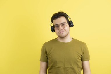 Sarı duvarın üzerinde duran kulaklıklı yakışıklı genç adam. Yüksek kalite fotoğraf