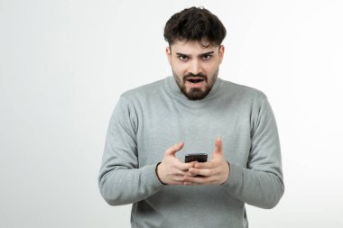 Akıllı telefonu beyaz duvara dayayan çekici adamın portresi. Yüksek kalite fotoğraf