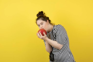 Down sendromlu sevimli bir kızın kırmızı nar yemesi. Yüksek kalite fotoğraf