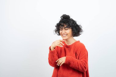 Kırmızı kazaklı kıvırcık güzel kadın ayakta ve poz veriyor. Yüksek kalite fotoğraf