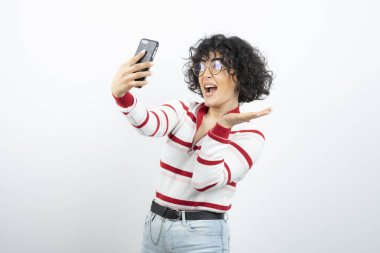 Kıvırcık saçlı genç kadın cep telefonundan selfie çekiyor. Yüksek kalite fotoğraf