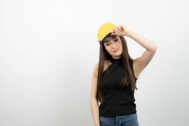 Sarı şapkalı genç beyaz duvarda kameraya bakıyor. Yüksek kalite fotoğraf