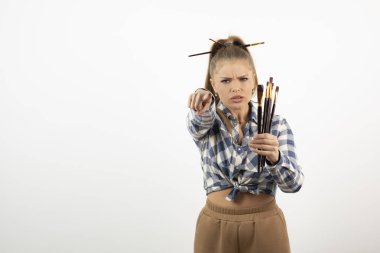 Kamerayı işaret eden ve elinde fırça tutan genç bir sanatçının portresi. Yüksek kalite fotoğraf