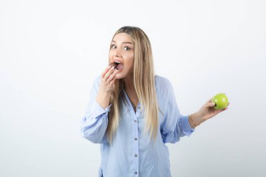 Beyaz arka planda yeşil elma tutan uzun saçlı genç bir kadının portresi. Yüksek kalite fotoğraf