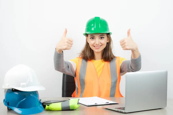 Arbeiterinnen Uniform Sitzen Schreibtisch Und Zeigen Daumen Hoch Hochwertiges Foto — Stockfoto