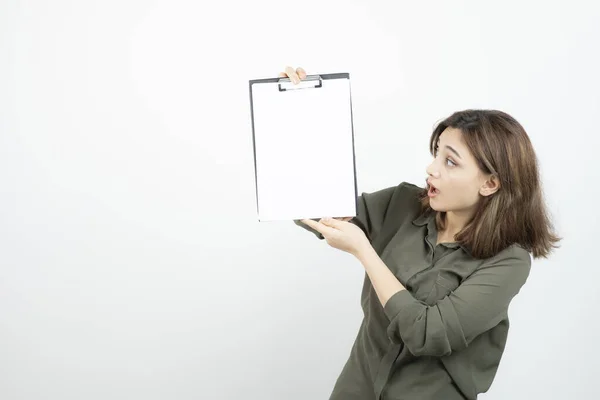 Hermosa Mujer Sujetando Portapapeles Mirándolo Por Encima Pared Blanca Foto — Foto de Stock