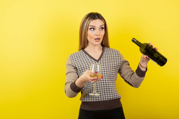 young beautiful woman with a glass of champagne on a yellow background