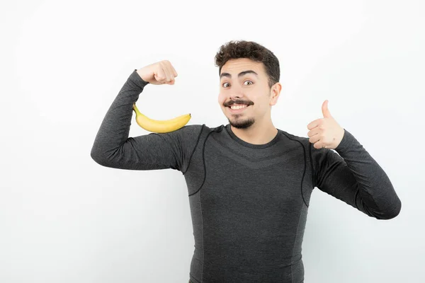 Joven Hombre Deportivo Guapo Sosteniendo Plátano Mostrando Pulgar Hacia Arriba —  Fotos de Stock