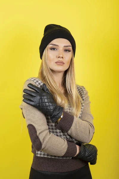 beautiful woman in a yellow sweater and gloves on yellow background