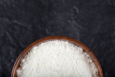 Siyah arkaplana yerleştirilmiş un dolu tahta bir kase. Yüksek kalite fotoğraf